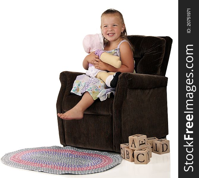 An adorable preschooler hugging her doll while sitting in a child-sized plush chair. A braided rug and pile of alphabet blocks are on the floor nearby. An adorable preschooler hugging her doll while sitting in a child-sized plush chair. A braided rug and pile of alphabet blocks are on the floor nearby.