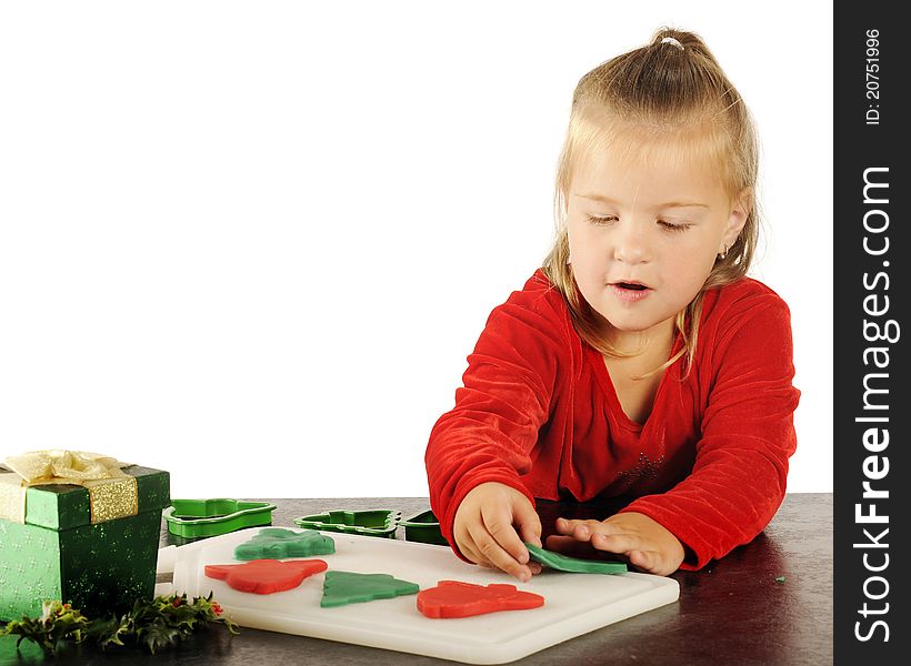 A cute preschooler happily cutting out red and green children's dough cookies for Christmas. Image has plenty of white space for your test. A cute preschooler happily cutting out red and green children's dough cookies for Christmas. Image has plenty of white space for your test.