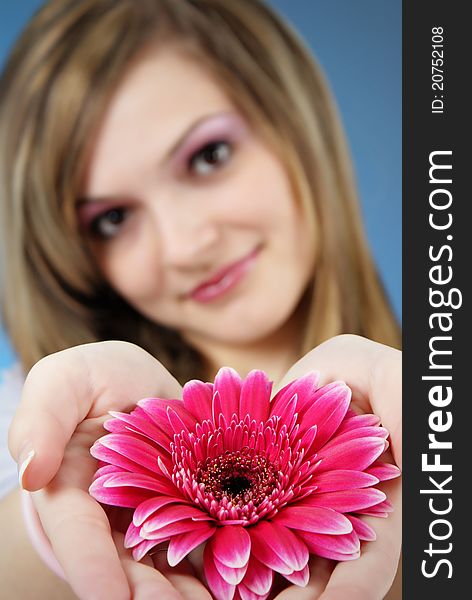Attractive smiling woman portrait with flower in her hand on blue background