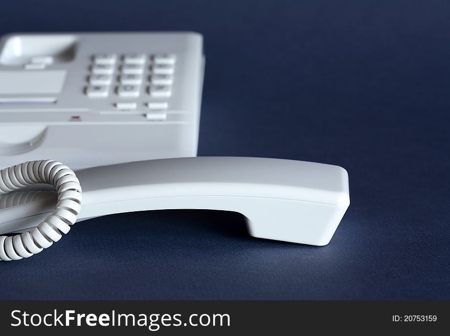 Receiver near ordinary push-button telephone on dark background