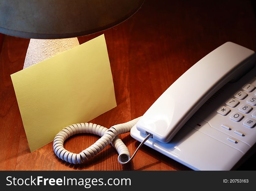 Blank paper sheet near telephone and luminous desk lamp. Blank paper sheet near telephone and luminous desk lamp