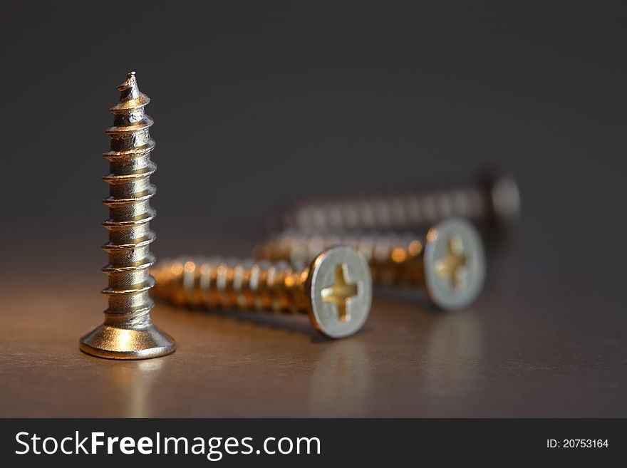 Extreme closeup of few brass screws on dark background. Extreme closeup of few brass screws on dark background