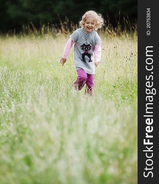 Running little girl across a meadow