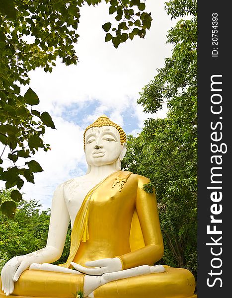 White & yellow sitting Budha image with blue sky at Hua Hin