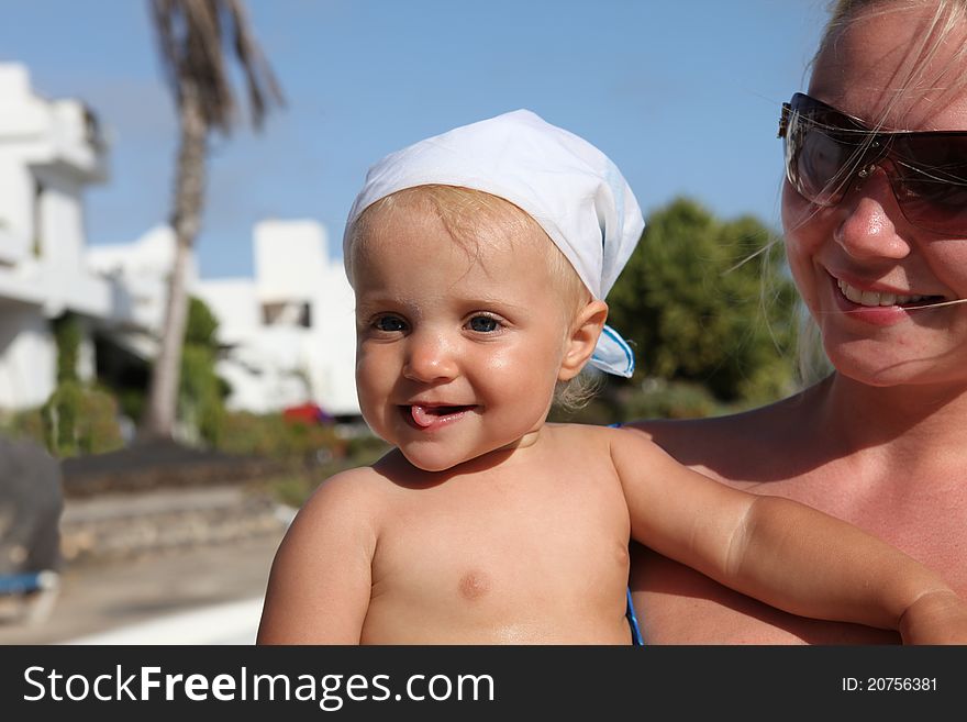 Portrait of smilling mother and daughter near pool. Focus on the baby