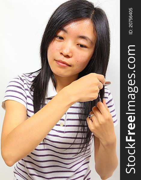 Young chinese woman brushing her hair. White background