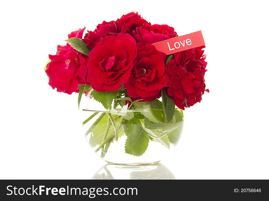 Close-up of a beautiful bouquet of red roses in a round glass vase. Isolated