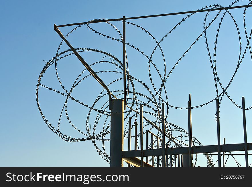 Fence of barbed wire. Against the blue sky