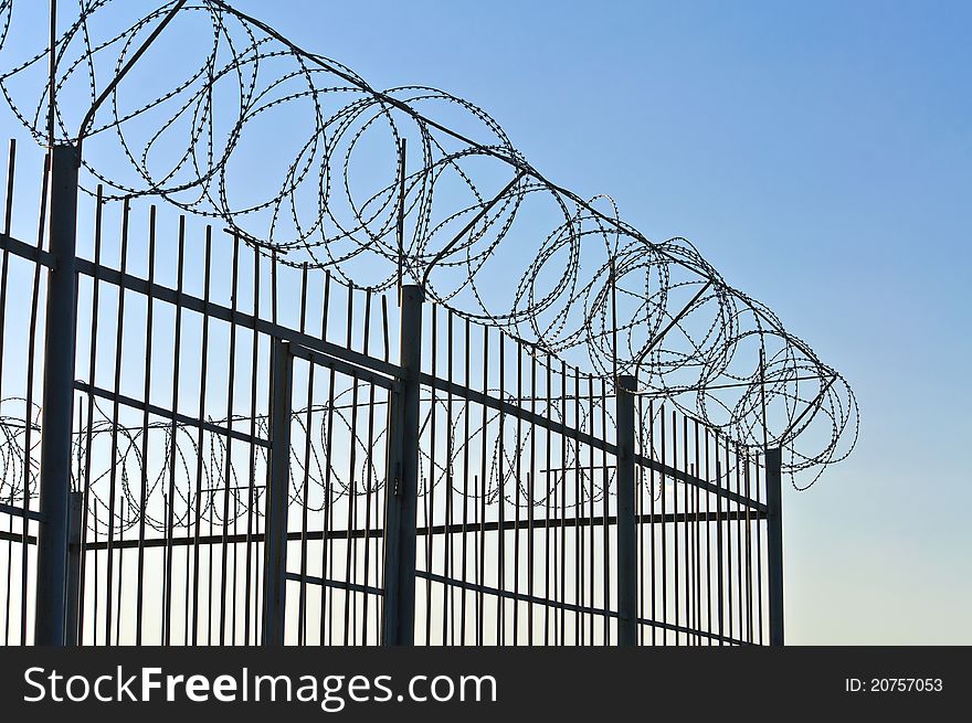 Fence of barbed wire. Against the blue sky