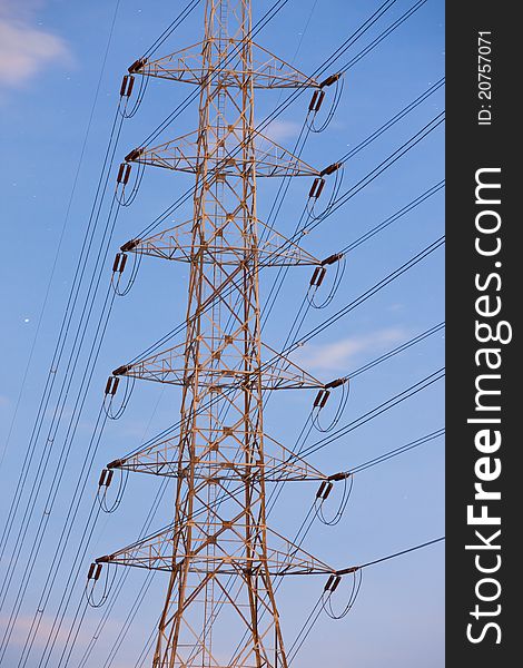 Electricity supply pylons in countryside on blue sky background
