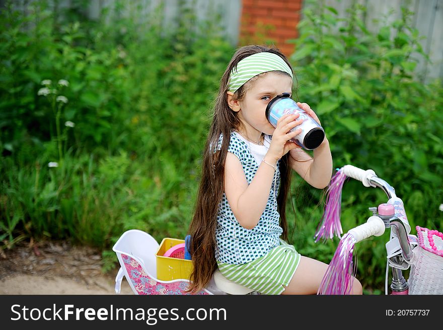 Long-haired Child Girl Drinks While Riding Bike