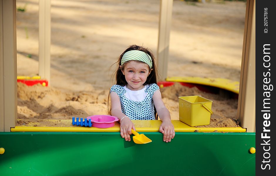 Happy child girl is playing in a sandbox