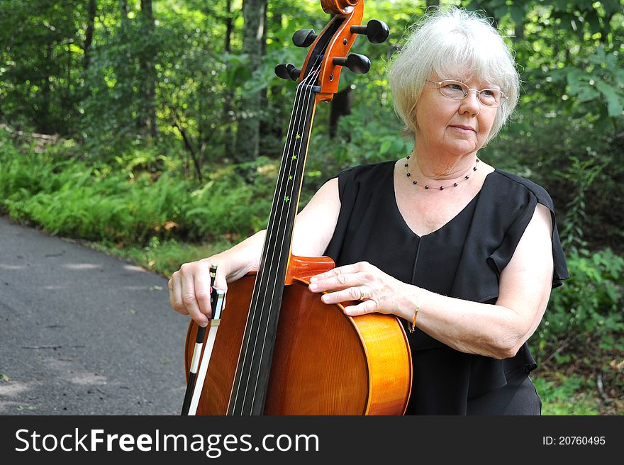 Music teacher posing with her cello outdoors. Music teacher posing with her cello outdoors.
