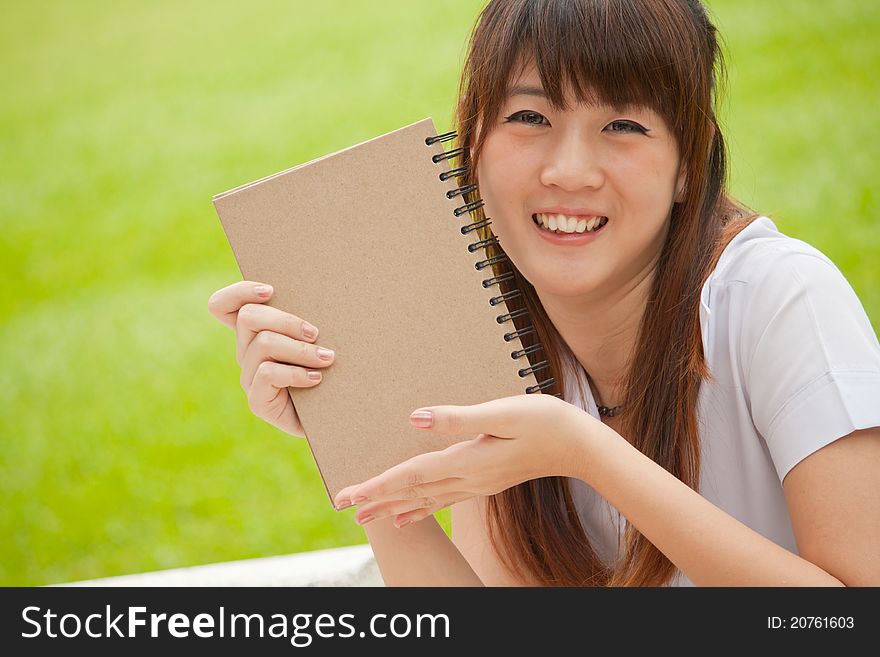 Asian girl smiling and holding her notebook