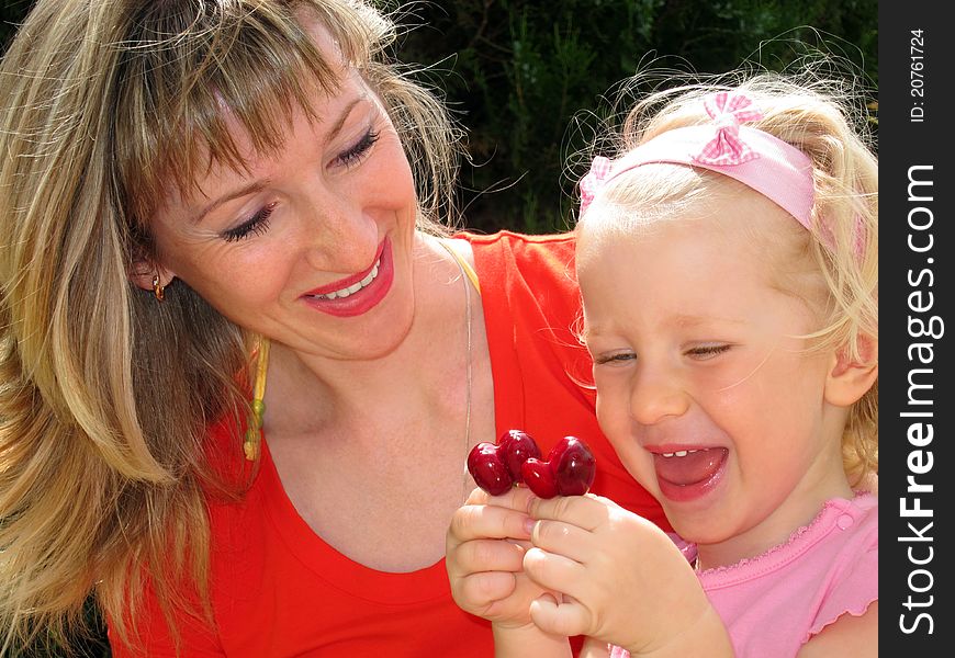 Mother with little daughter looks at unusual cherries. Mother with little daughter looks at unusual cherries