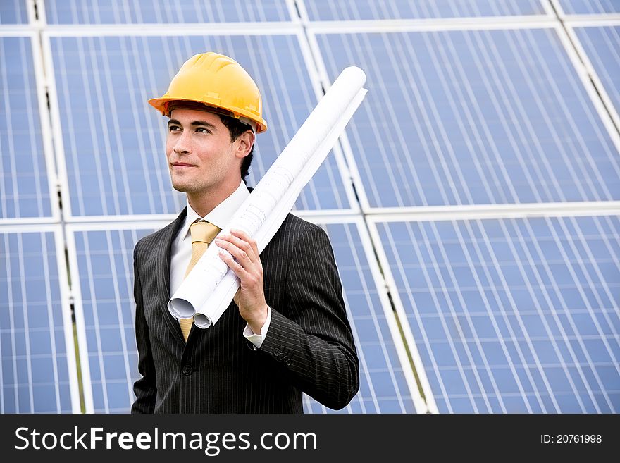 Male engineer at solar power station holding blueprints.
