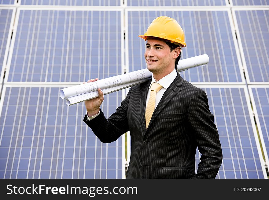 Male engineer at solar power station holding blueprints.