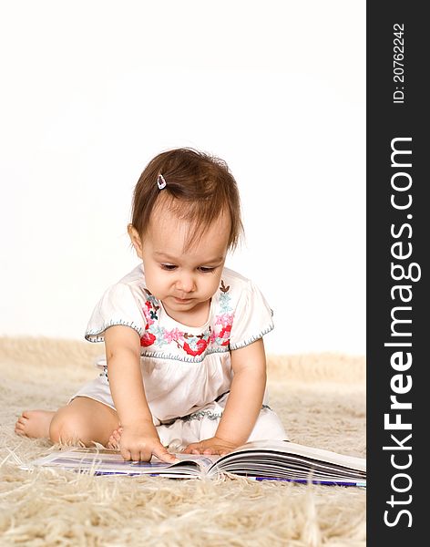 Little girl reading a book on a carpet