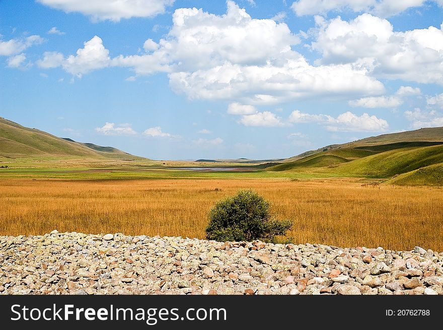 Valley in mountains with a yellow grass and the blue sky