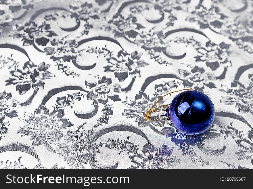 Blue Christmas bauble on ornate silver paper. Blue Christmas bauble on ornate silver paper.