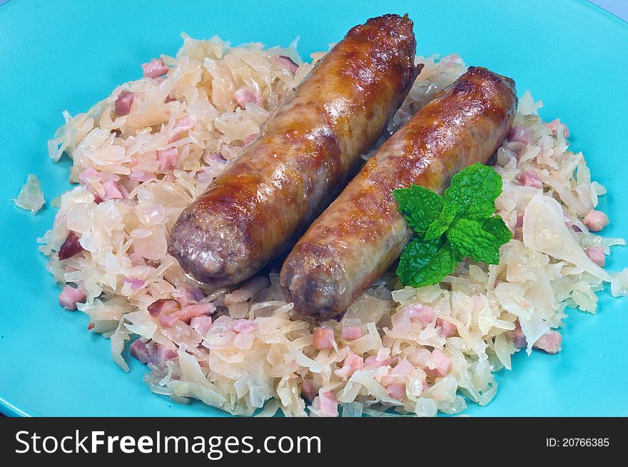 Two sausages on a plate with sauerckraut