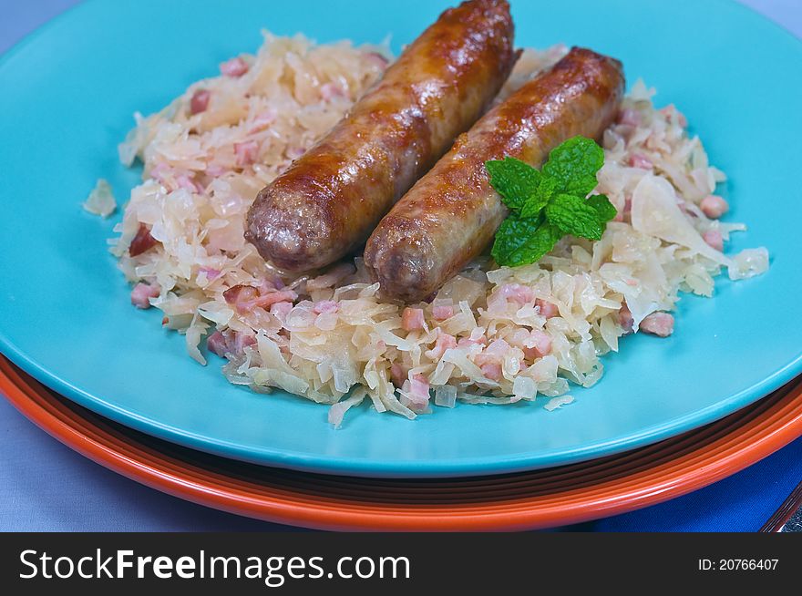 Two sausages on a plate with sauerckraut