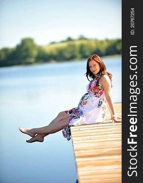 Woman sitting at jetty. summer's day on lakeside. Woman sitting at jetty. summer's day on lakeside