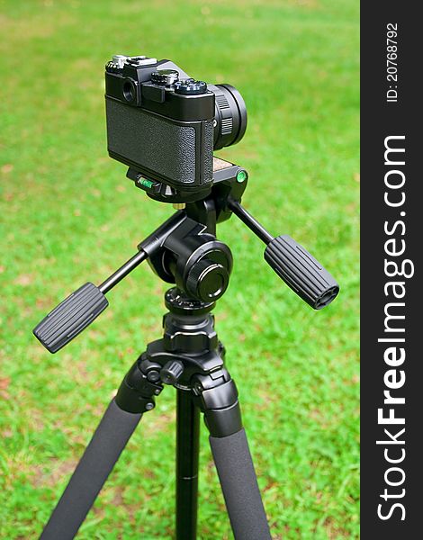 The camera is mounted on a tripod, standing on the grass. The camera is mounted on a tripod, standing on the grass