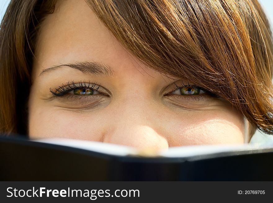 The girl's face looks out because of the book close up
