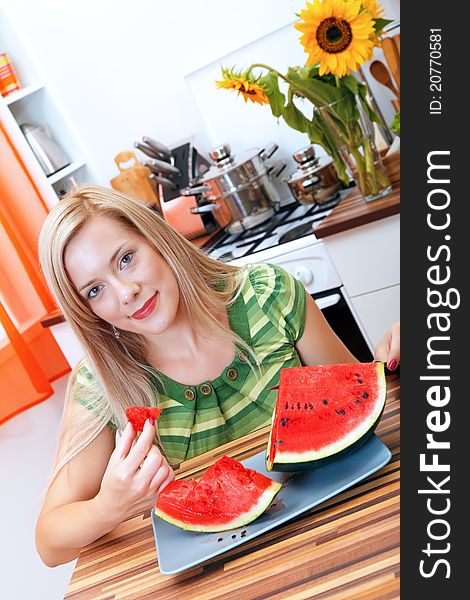 Young woman eating watermelon in the kitchen. Young woman eating watermelon in the kitchen