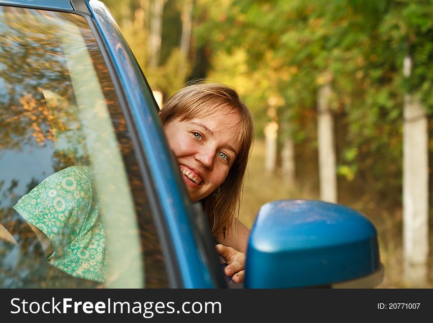 Young woman looking from the car window smiling. Young woman looking from the car window smiling