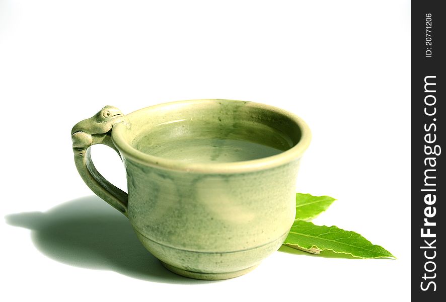 A nice hand-crafted cup of tea with focus on the frog and the leafs. On a white backgrpund. A nice hand-crafted cup of tea with focus on the frog and the leafs. On a white backgrpund