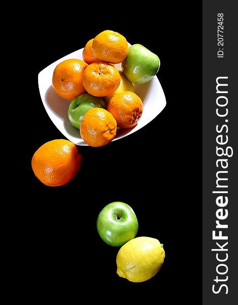 Mandarins, oranges, apples and lemons in a ceramic bowl, on a black background. Mandarins, oranges, apples and lemons in a ceramic bowl, on a black background