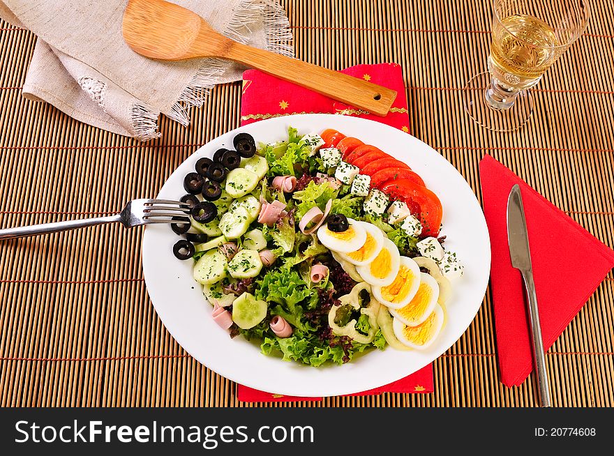 Italian Cesar salad on table with white wine glass, knife and fork