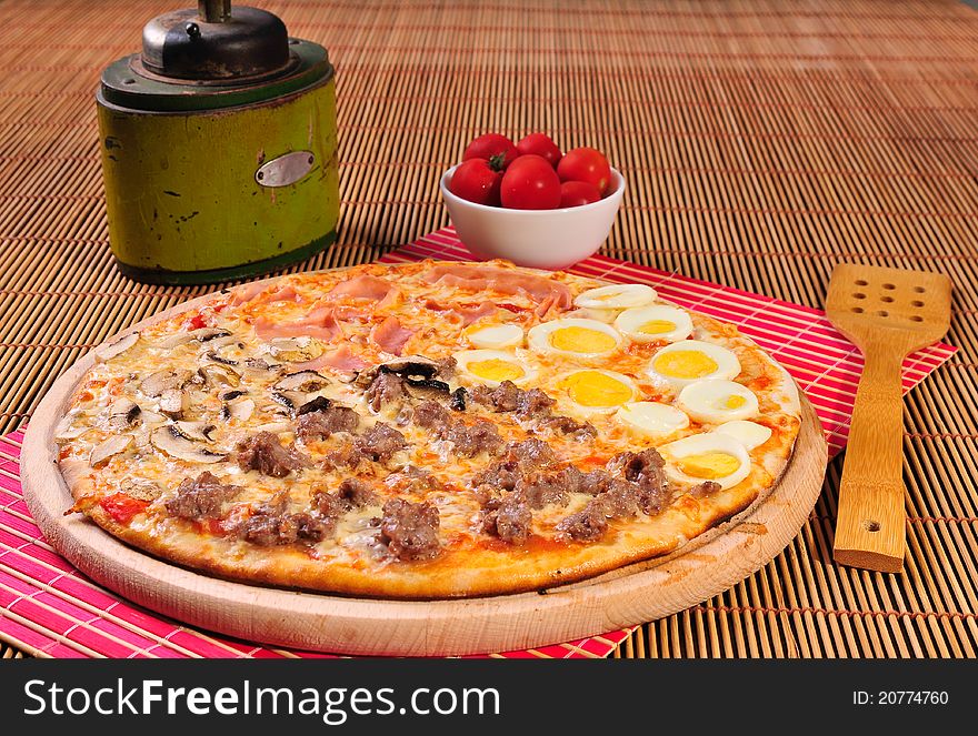 Italian quatro stagioni salami pizza on table and pepper mill and tomatoes. Italian quatro stagioni salami pizza on table and pepper mill and tomatoes