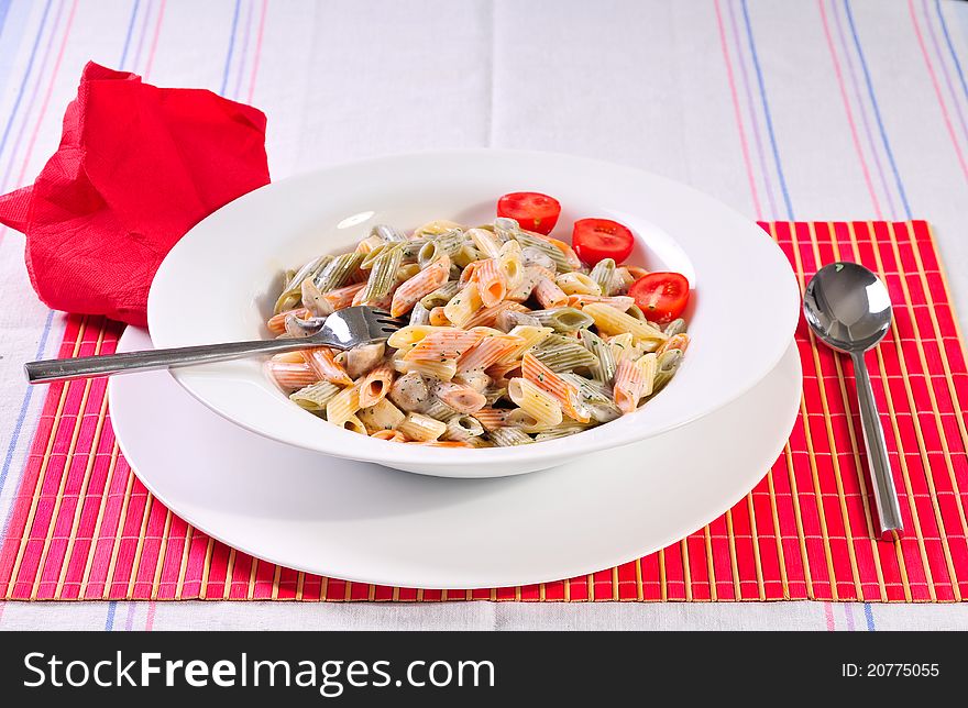 Italian spaghetti pasta on table with red tomatoes, spoon and fork