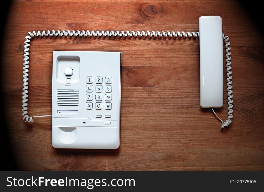 Gray ordinary push-button telephone on wooden surface. Gray ordinary push-button telephone on wooden surface