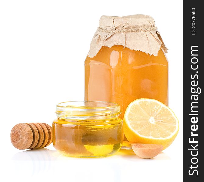 Jar full of honey and lemon on white background