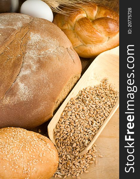 Bakery products and wheat grain on wooden texture