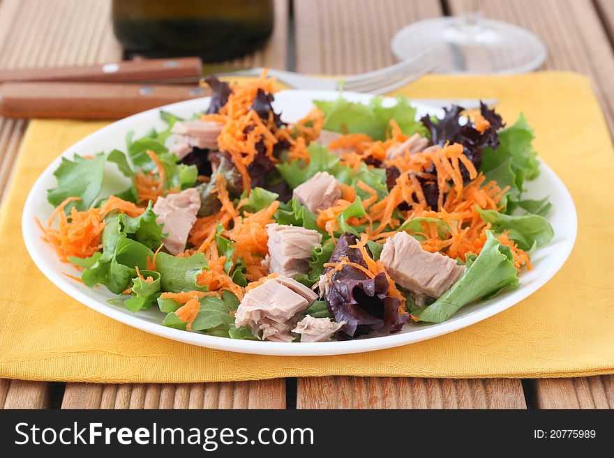 Salad with tuna, glass and bottle of wine