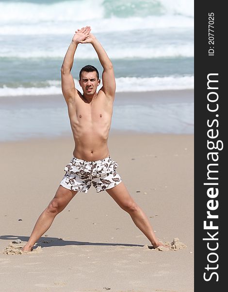 Attractive man making stretching movements before run on the beach