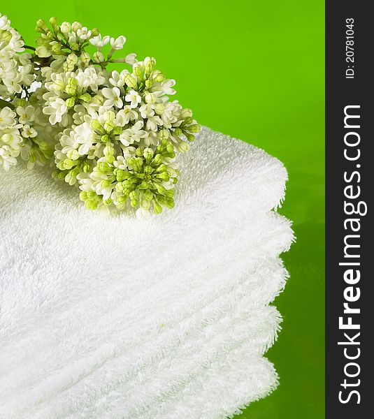 Pile white towels on green background and branch white lilac