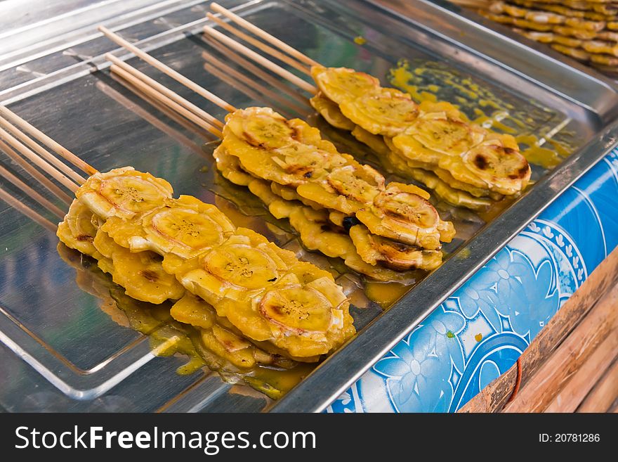 Grilled bananas stack with sticks with sweet sauce on metal plate. Grilled bananas stack with sticks with sweet sauce on metal plate