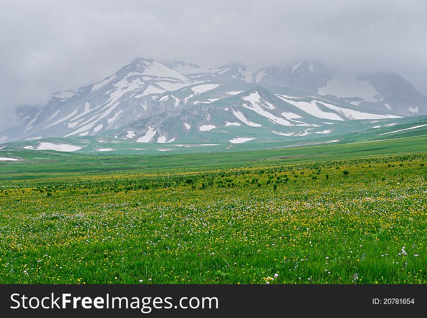 Summer landscape with green grass, mountains and clouds. North Caucasus mountains
