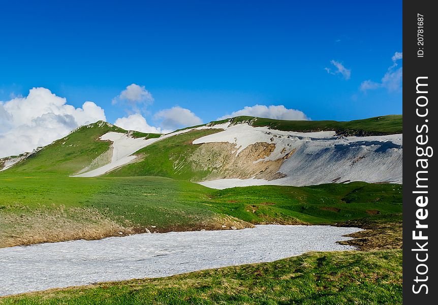 Summer landscape with green grass, mountains and clouds. North Caucasus mountains. Summer landscape with green grass, mountains and clouds. North Caucasus mountains