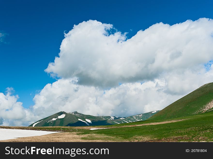 Summer landscape with green grass, mountains and clouds. North Caucasus mountains. Summer landscape with green grass, mountains and clouds. North Caucasus mountains