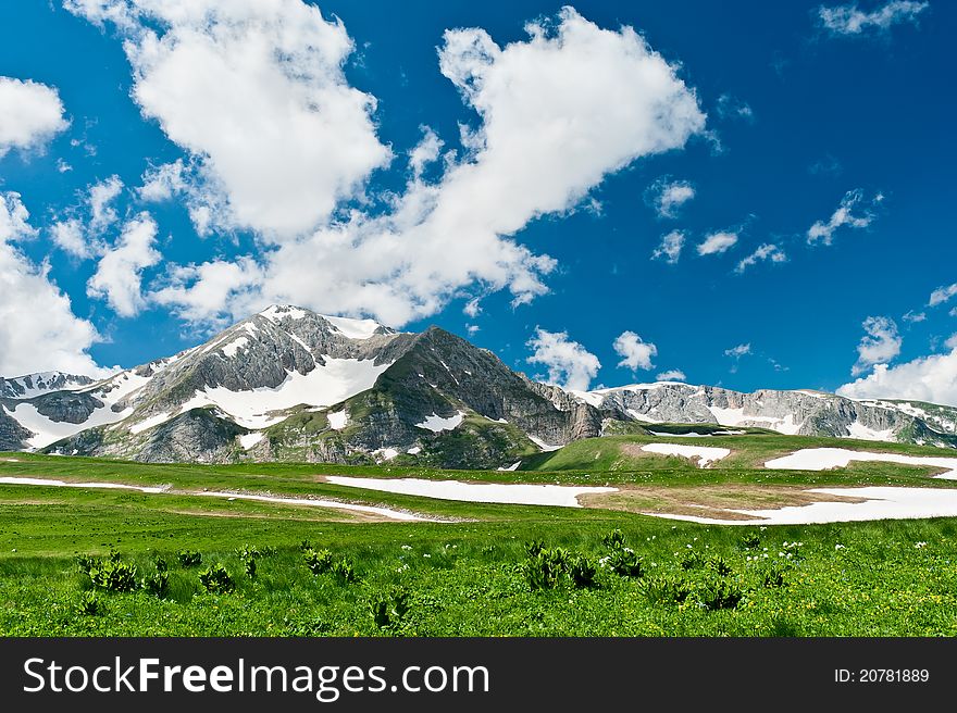 Summer landscape with green grass, mountains and clouds. North Caucasus mountains. Summer landscape with green grass, mountains and clouds. North Caucasus mountains
