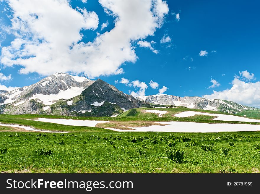 Summer landscape with green grass, mountains and clouds. Mountains in the North Caucasus. Summer landscape with green grass, mountains and clouds. Mountains in the North Caucasus