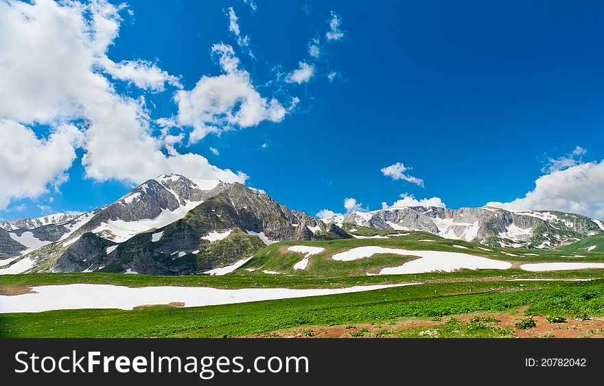 Summer landscape with green grass, mountains and clouds. Mountains in the North Caucasus. Summer landscape with green grass, mountains and clouds. Mountains in the North Caucasus