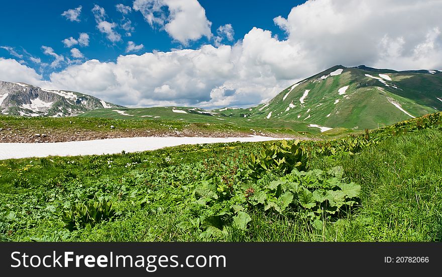 Summer landscape with green grass, mountains and clouds. Mountains in the North Caucasus. Summer landscape with green grass, mountains and clouds. Mountains in the North Caucasus